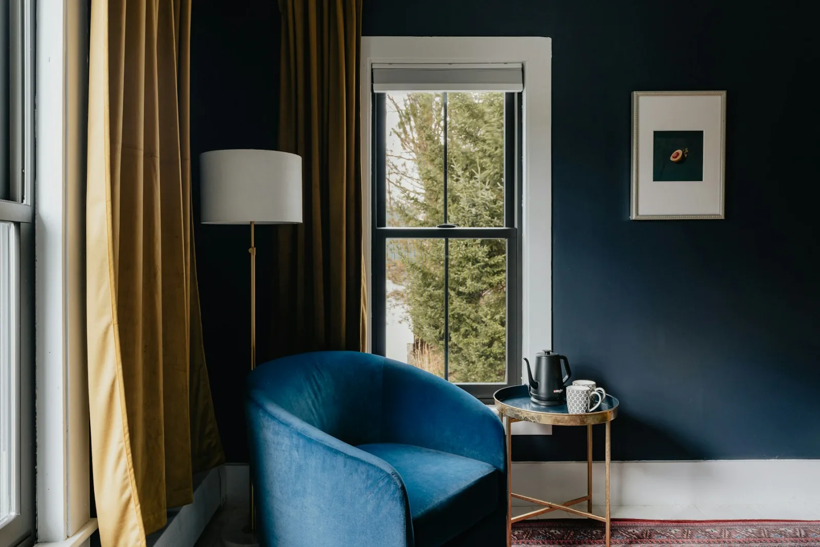 Lampadaire droit à côté d'un fauteuil bleu près d'une fenêtre