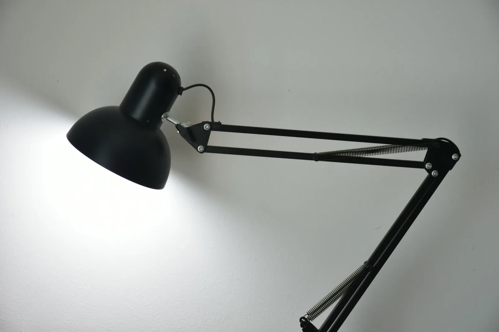 Lampe d'architecte noire orientée vers un mur blanc