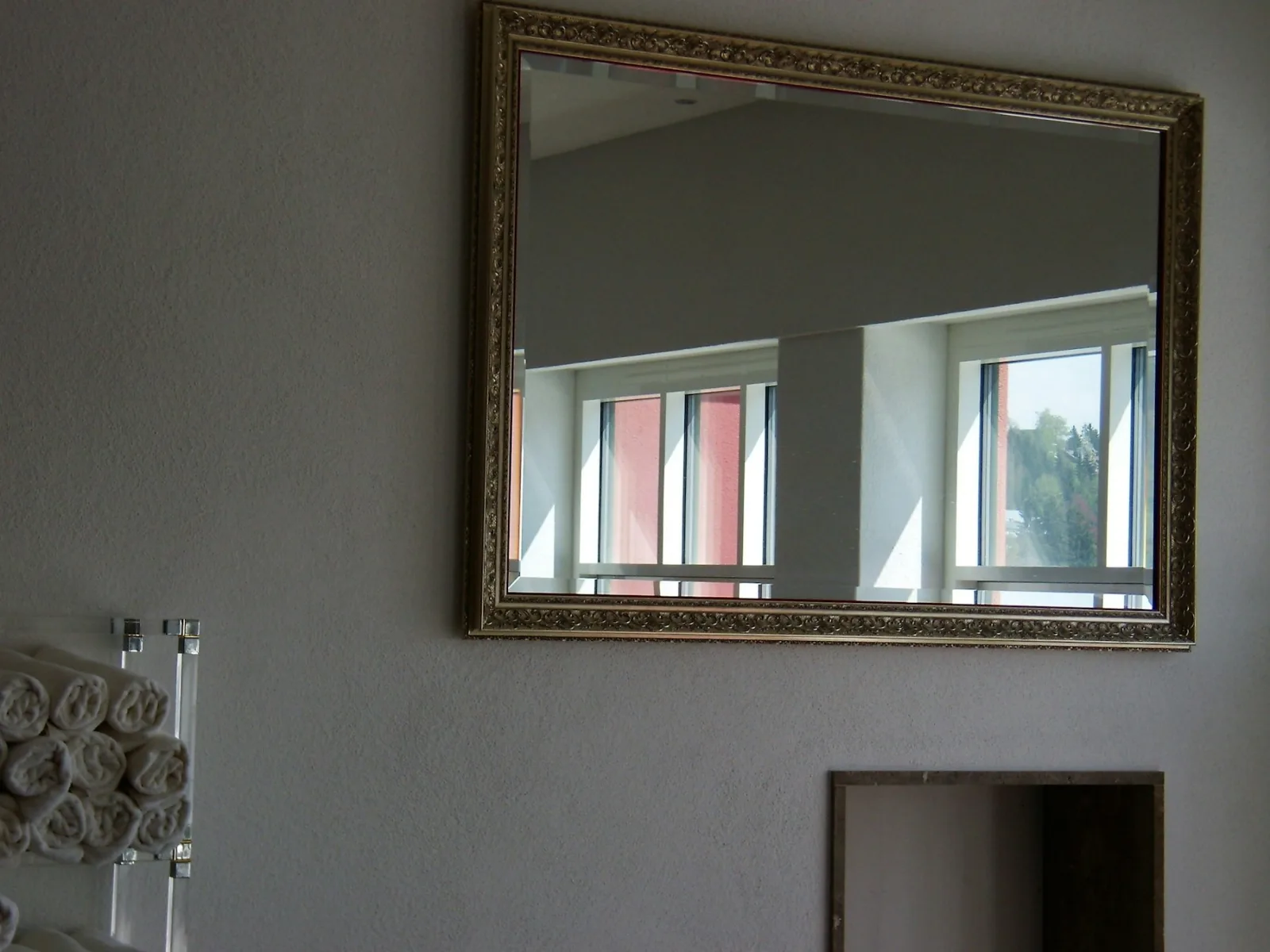 Grand miroir à cadre doré fixé sur un mur gris