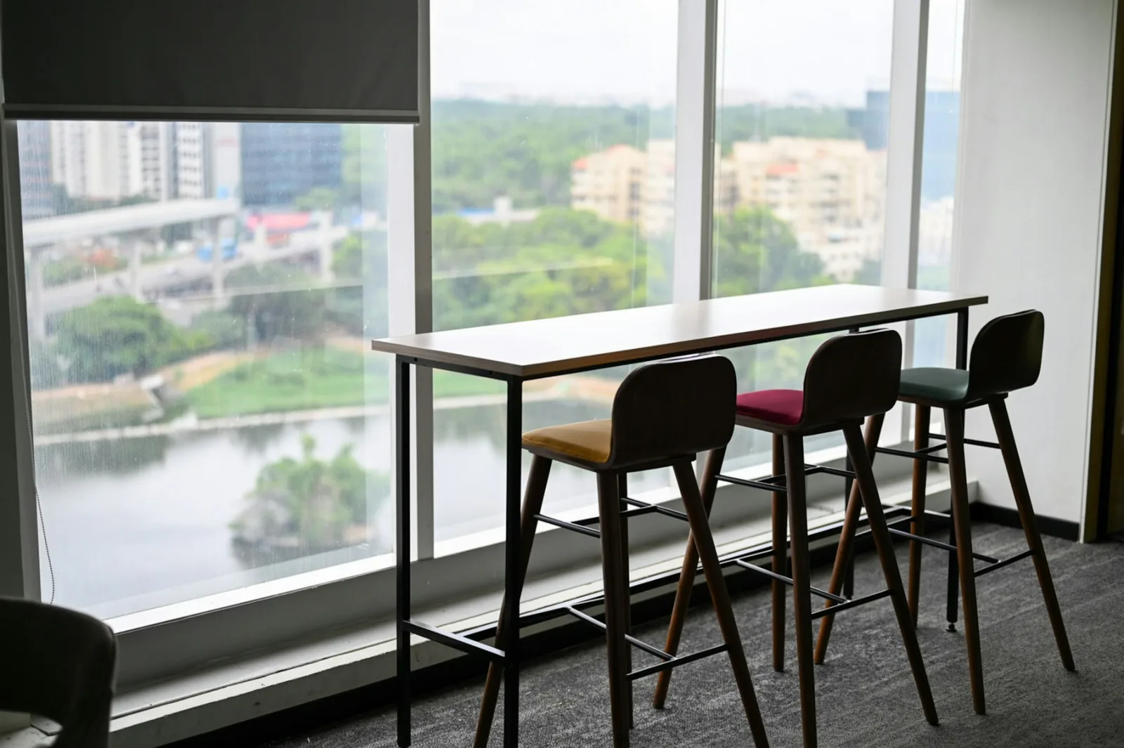 Table haute devant une baie vitrée avec des tabourets à repose-pied