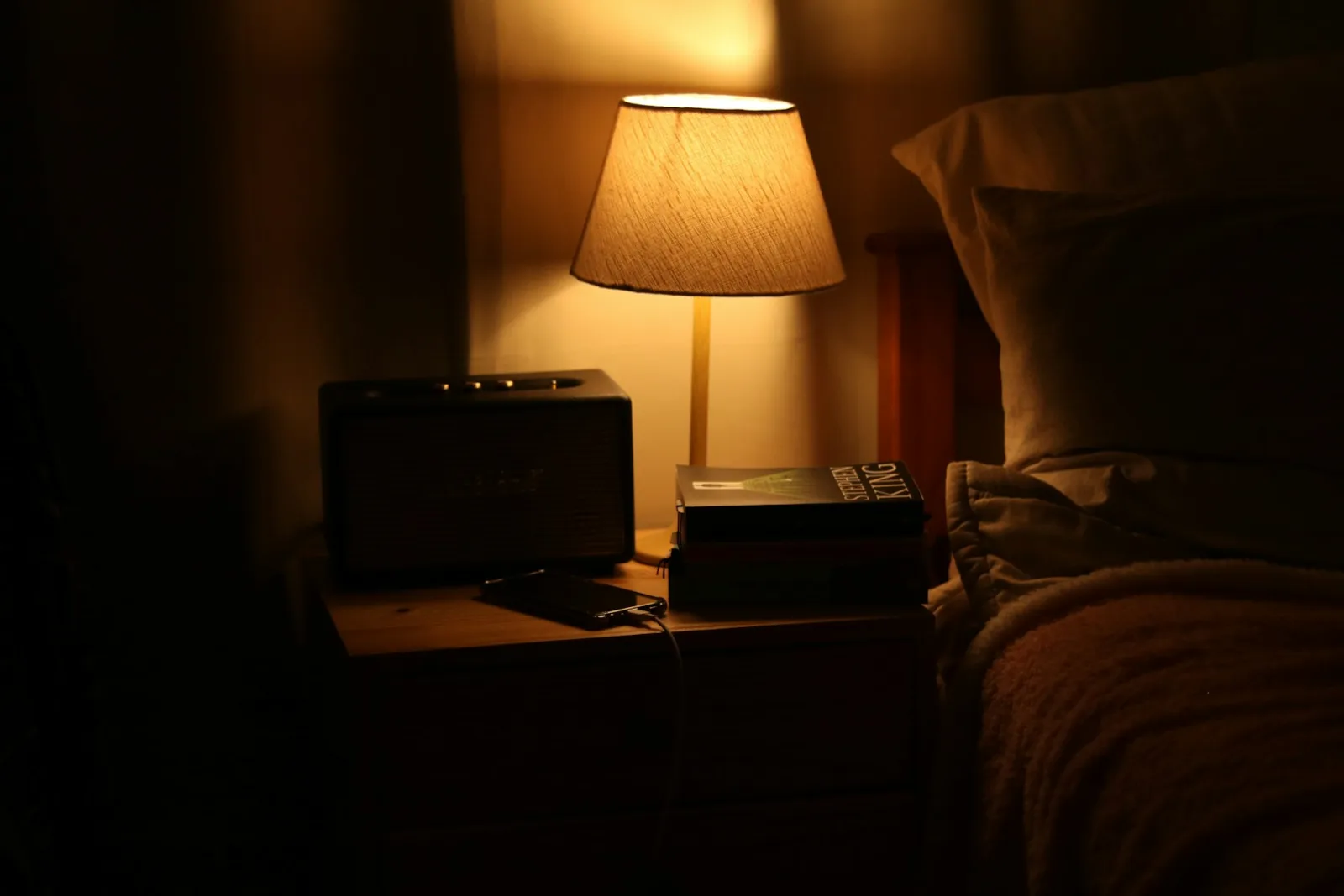Chambre dans la pénombre éclairée par une lampe de chevet à la lumière chaude