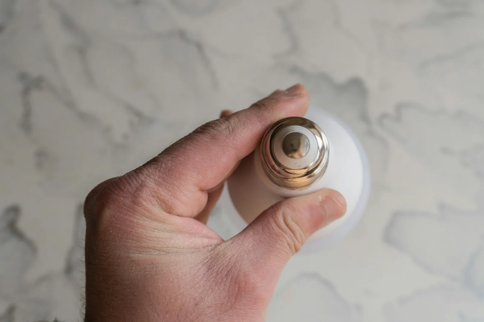 Main qui tient une ampoule LED et montre son culot à vis