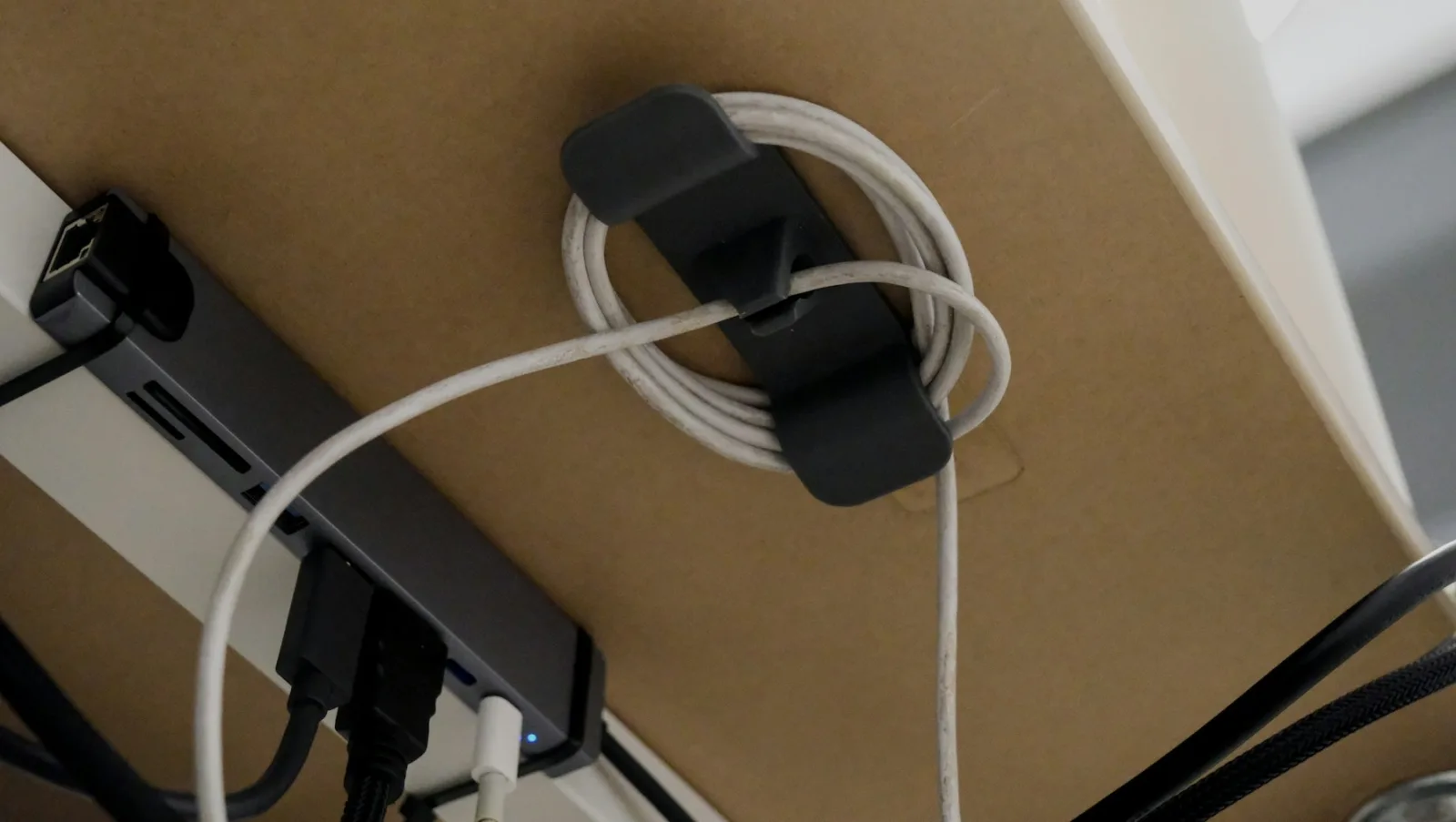 Câbles regroupés par un passe-câble sous un plateau de bureau