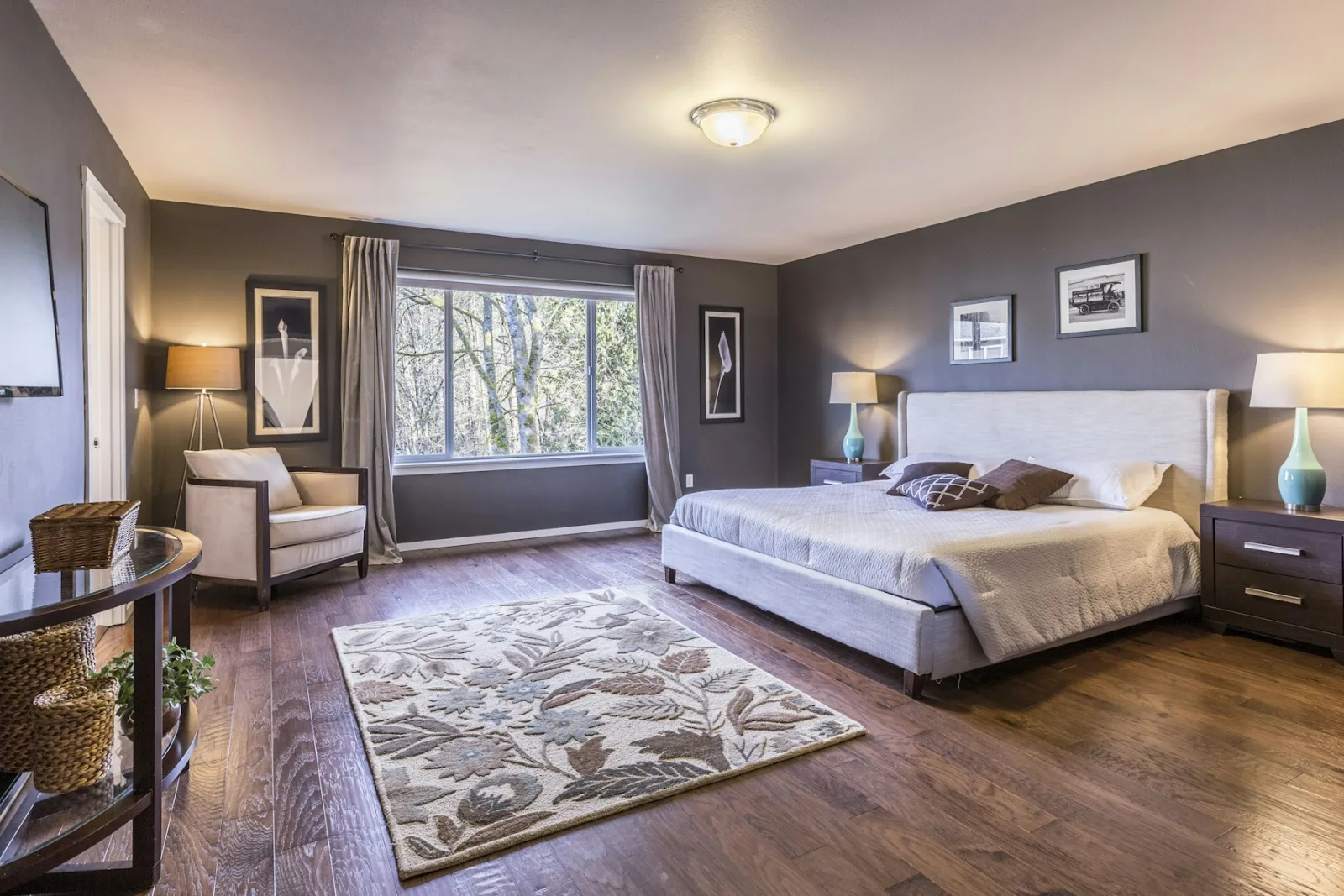Chambre avec un grand lit posé sur un tapis à motifs qui dépasse au pied et sur les côtés