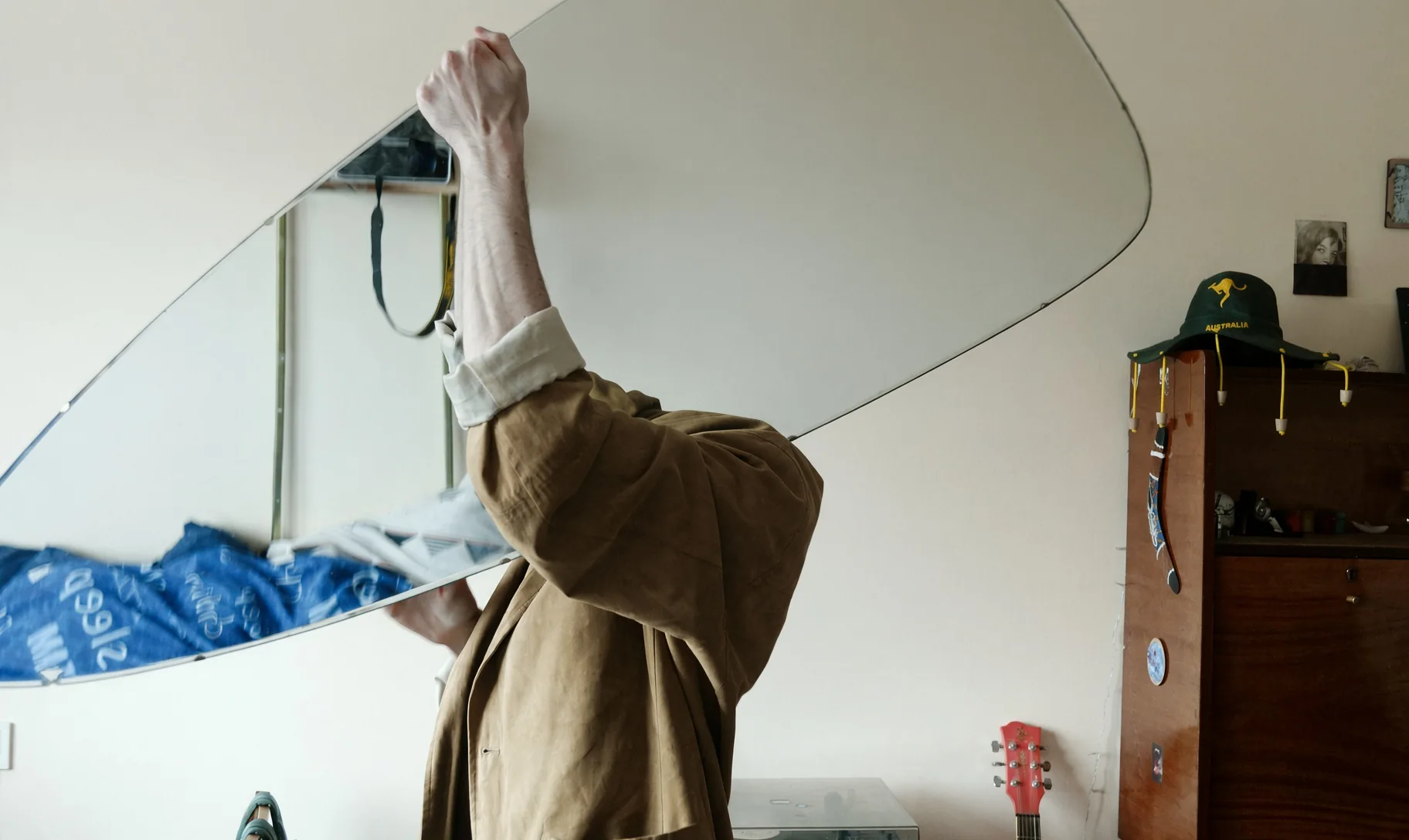Homme qui porte un grand miroir aux bords arrondis pour l'accrocher